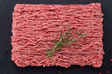 raw minced meat and spices on dark background, top view