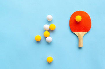 Red racket for table tennis with yellow white balls on blue background. Ping pong sports equipment...