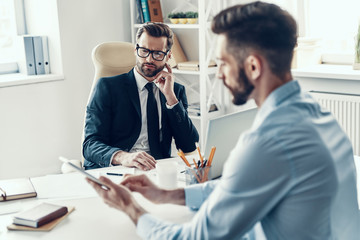 Two good looking young men in formalwear communicating together