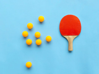 Red racket for table tennis with yellow balls on blue background. Ping pong sports equipment in minimal style. Flat lay, top view, copy space