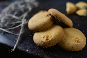 Homemade shortbread, round-shaped pastry on a dark old surface in a stack of crumbs. And the village threads of burlap