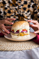 delicious vegan burger in a plate and woman hands