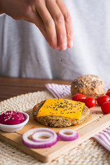 woman hands throwing seeds into cheddar cheese burger