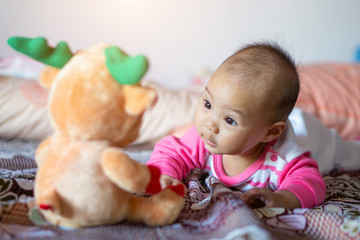 Fototapeta na wymiar 6 month old Asian baby girl is smiling, enjoying his doll.