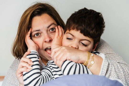 un ni&ntilde;o y una mujer (hijo y mare) juegan a cuc&uacute; (esconderse entre las manos tap&aacute;ndose los ojos) el adulto coge las manos del peque&ntilde;o para poder jugar. el chico tiene una discapacidad. est&aacute;n alegres.