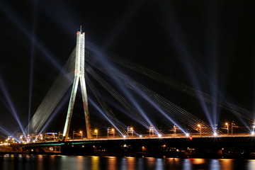 Illuminated cable-stayed bridge over the river at night.