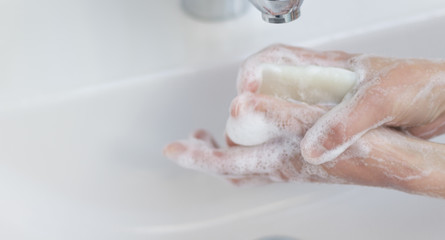 woman washing hands in sink under water tap