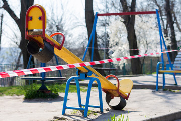 Fototapeta na wymiar Barrier tape on a children's swing. Indoor playground for quarantine. KOVID 19.