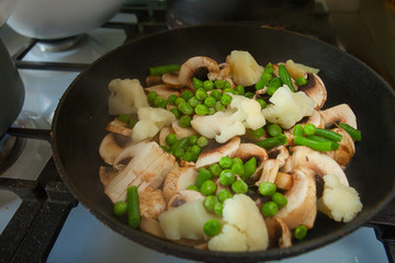 Champignons cauliflower peas peas and green beans stewed in  black skillet