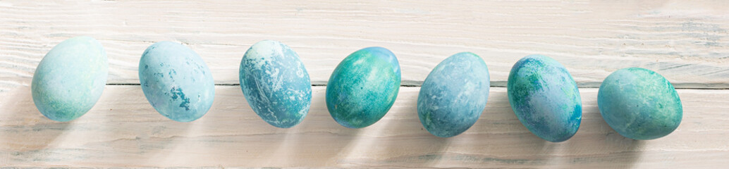 on a white background in a yellow plate are blue marble eggs lie as an Easter symbol