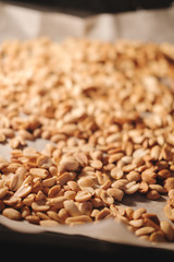 Peanut beans are fried on baking sheet and parchment paper in the oven. Preparing to make homemade peanut butter at home.