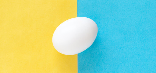 Easter egg on colorful bright yellow and blue background, wide banner