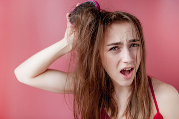 Young beautiful girl having problems while hair on pink background