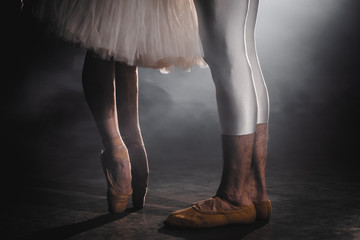 Close up of ballet couple of dancers as they practices exercises on dark stage or studio. Woman's...