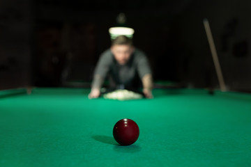 Game of billiards. The man puts the balls on the green billiard table.