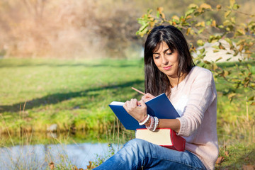 Fototapeta premium Beautiful Woman Studying Outdoor on a Lake Background 