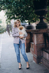 Beautiful young blond woman with her pet Pomeranian Spitz dog breed for a walk. Little fluffy dog. Soft selective focus.