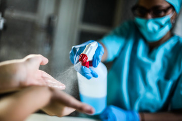 A doctor sprays disinfectant on kid's hands