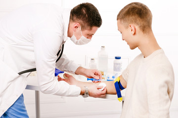 Doctors hands giving flu vaccine into the hand of young boy patient close up photo in clinic on white background. Doctor vaccinating infected young man. Injecting from corona virus, covid-19.