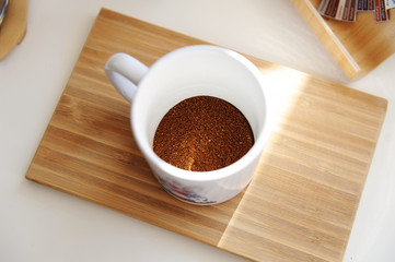 Brewing coffee in mug. Freshly ground coffee in a cup top view