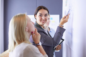 Business, education and office concept - business team with flip board in office discussing something.