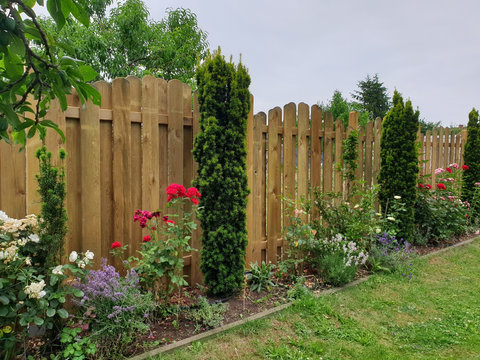Gartenzaun aus Holz als Sichtschutz mit einer Blumenrabatte