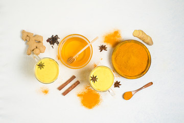 Obraz na płótnie Canvas Indian traditional Golden milk with turmeric, ginger, spices, honey. healing effect of the drink. ingredients for a Golden drink on a light background. antiviral antioxidant. the view from the top