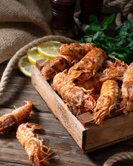 Prawns in a wooden box on a brown wooden table. Sclerocrangon salebrosa shrimp	