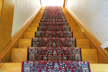 Stairs with red pattern carpet strip, old vintage wooden staircase, antique design