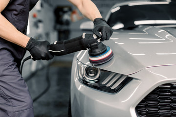 Car detailing and polishing concept. Hands of professional car service male worker, with orbital...