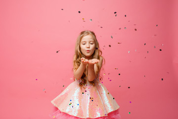happy Little girl blow confetti on pink background, holiday concept