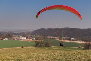 A paraglider´s  funny flight start on a meadow with blue sky on the spring 