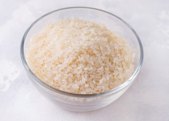Raw uncooked rice closeup in a glass bowl on a white background
