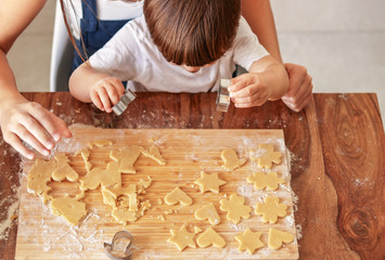 Top view of little child making homemade cookies together with mother at home. Children leisure activity at quarantine. Family bonding, cooking, quality time.