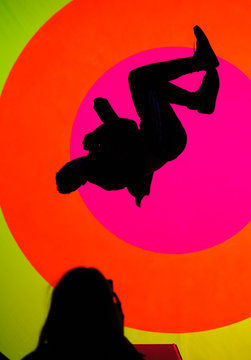 Young, attractive fit man, making a sideflip, showing his flexibility and skills. Oval and colorful texture in background 