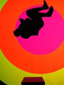 Young, attractive fit man, making a sideflip, showing his flexibility and skills. Oval and colorful texture in background 