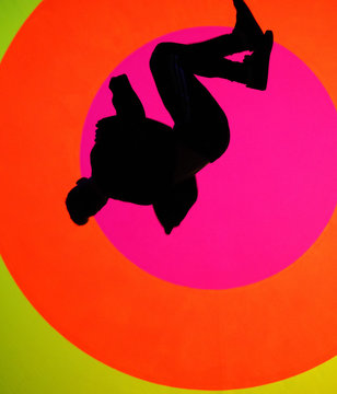 Young, attractive fit man, making a sideflip, showing his flexibility and skills. Oval and colorful texture in background 