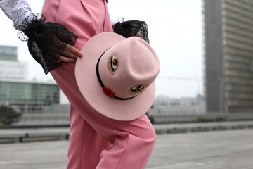 Faceless female figure in pink trouser with pink hat in hands on street in Paris. Fashionable...