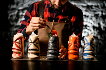 Professional barman decorates colored ceramic glass by slice of citrus