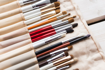 Fototapeta premium Makeup, beauty and cosmetics concept - Set of make-up brushes in a light case.