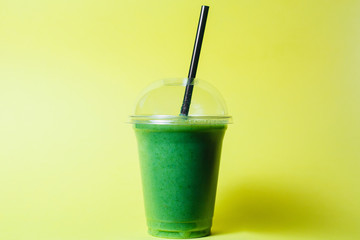 disposable cup of green smoothie with straw on studio background best