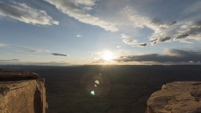 A stunning sunset timelapse of Canyonlands National Park as seen from Needles Overlook as clouds flow through the sky before lighting up orange in the distance.