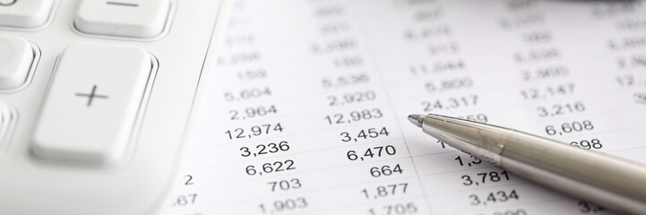 Silver pen report with numbers next to calculator