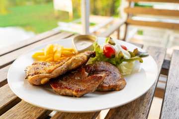Meat plate of steaks and fries. Chicken and meat on a plate with potatoes in a summer cafe.