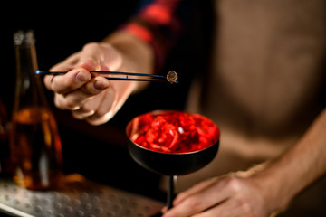 close-up. Bartender's hand gently decorates glass by plant