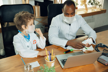Fototapeta premium Caucasian teenboy as a doctor consulting, giving recommendation, treating. Little doctor during discussing, studying with older colleague. Concept of childhood, human emotions, health, medicine.