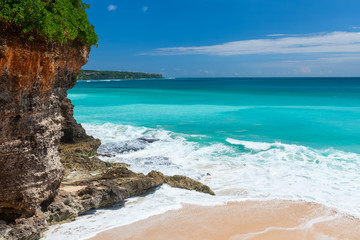 Balinese sandy beach with green steep cliff and torquoise water. Bali, Indonesia