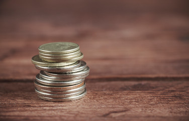 Coins stacked in a tower on a dark wooden background. Concept of saving money.