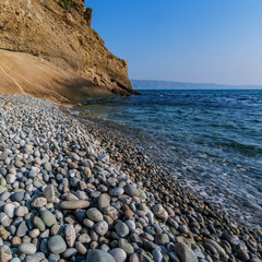 Deserted sea shore with pebbles on a sunny day with a blue sky.