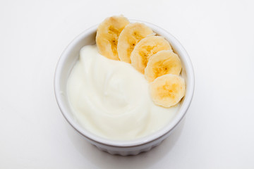 Healthy breakfast: yogurt with and banana in a white bowl on the white table